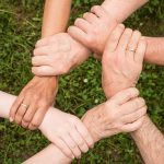 Six people from different ethnic backgrounds holding each others wrists